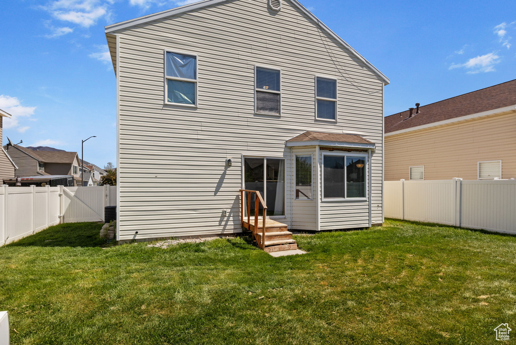 Rear view of house with a fenced backyard and a yard