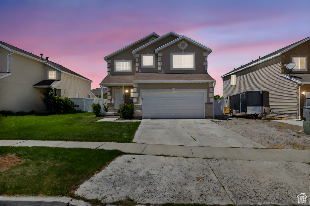 Traditional-style house featuring a lawn, fence, an attached garage, and driveway