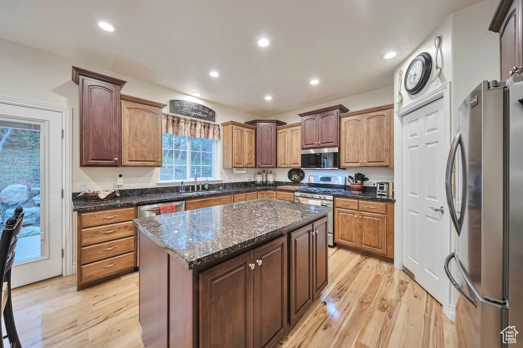 Kitchen with light wood-type flooring, a center island, appliances with stainless steel finishes, and a sink