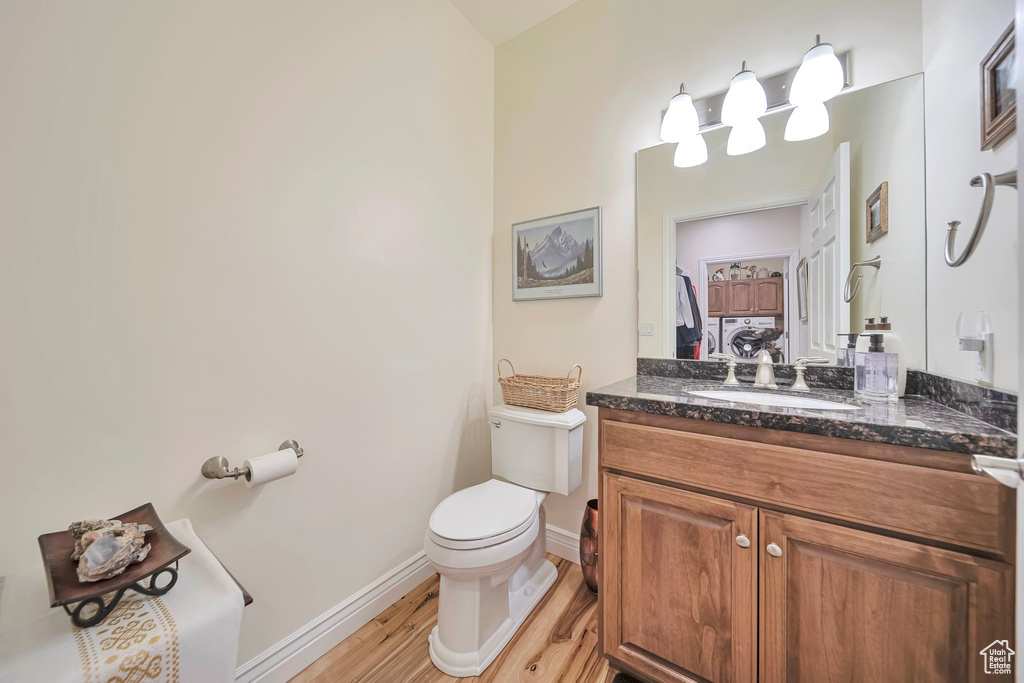 Bathroom featuring toilet, vanity, wood finished floors, and baseboards