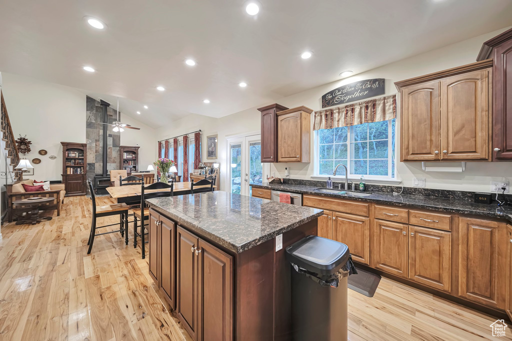 Kitchen with lofted ceiling, a sink, ceiling fan, a center island, and light wood finished floors