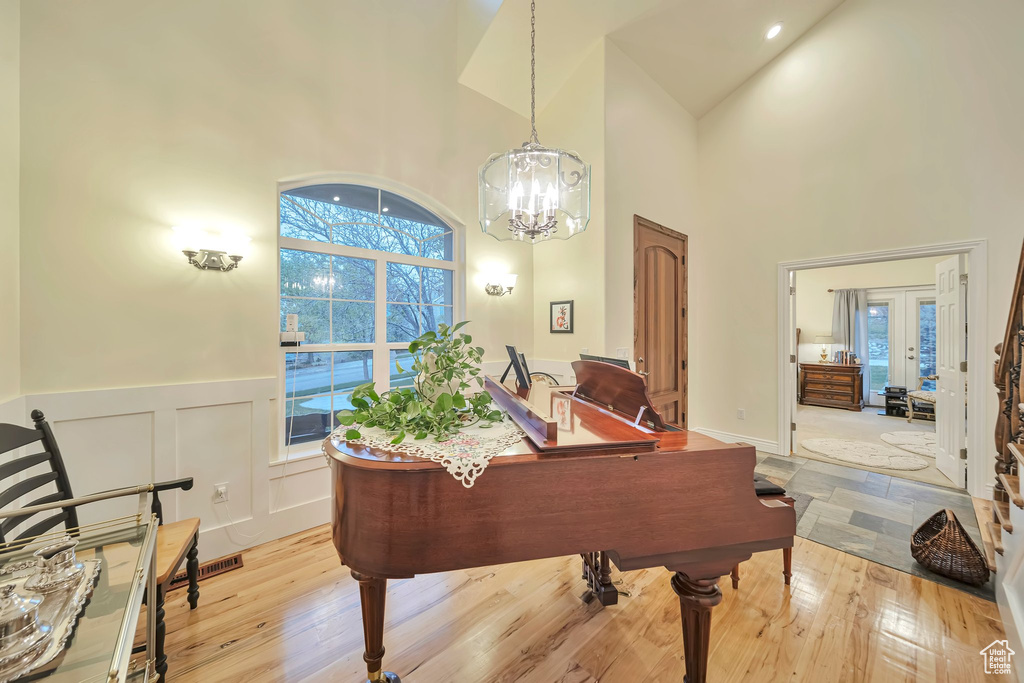 Office area featuring a high ceiling, a chandelier, a wainscoted wall, french doors, and wood finished floors