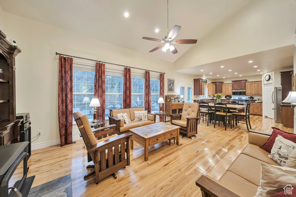 Living area with baseboards, ceiling fan, light wood-style floors, and plenty of natural light