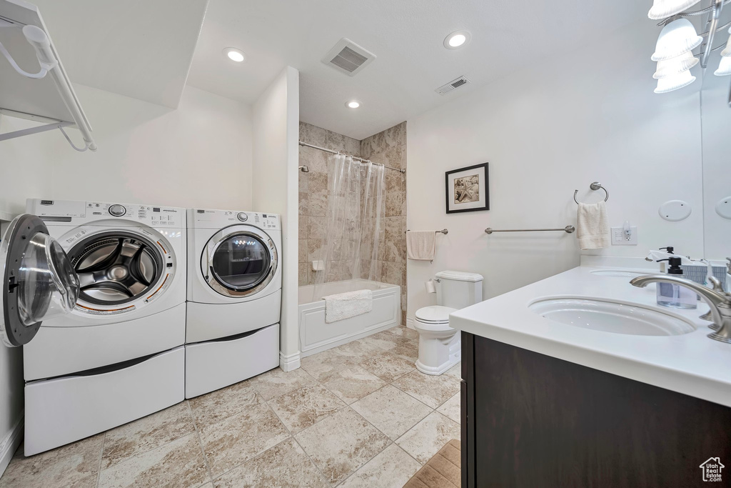 Full bathroom with independent washer and dryer, toilet, visible vents, and baseboards