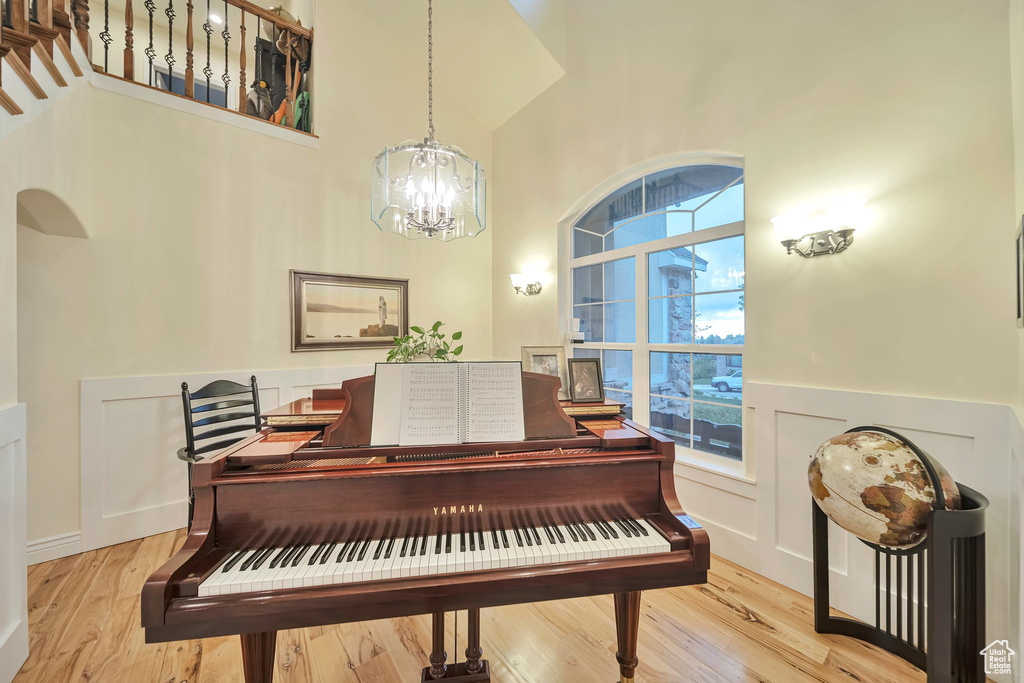 Sitting room featuring wood finished floors, a wainscoted wall, a chandelier, and a high ceiling