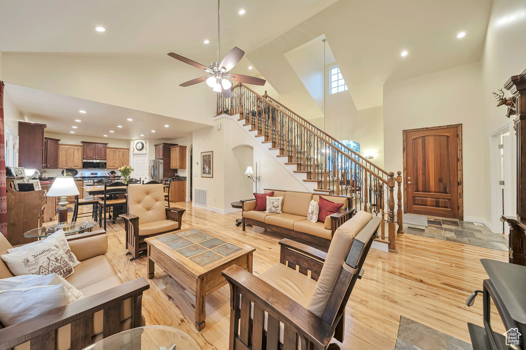 Living room featuring stairway, ceiling fan, recessed lighting, and high vaulted ceiling