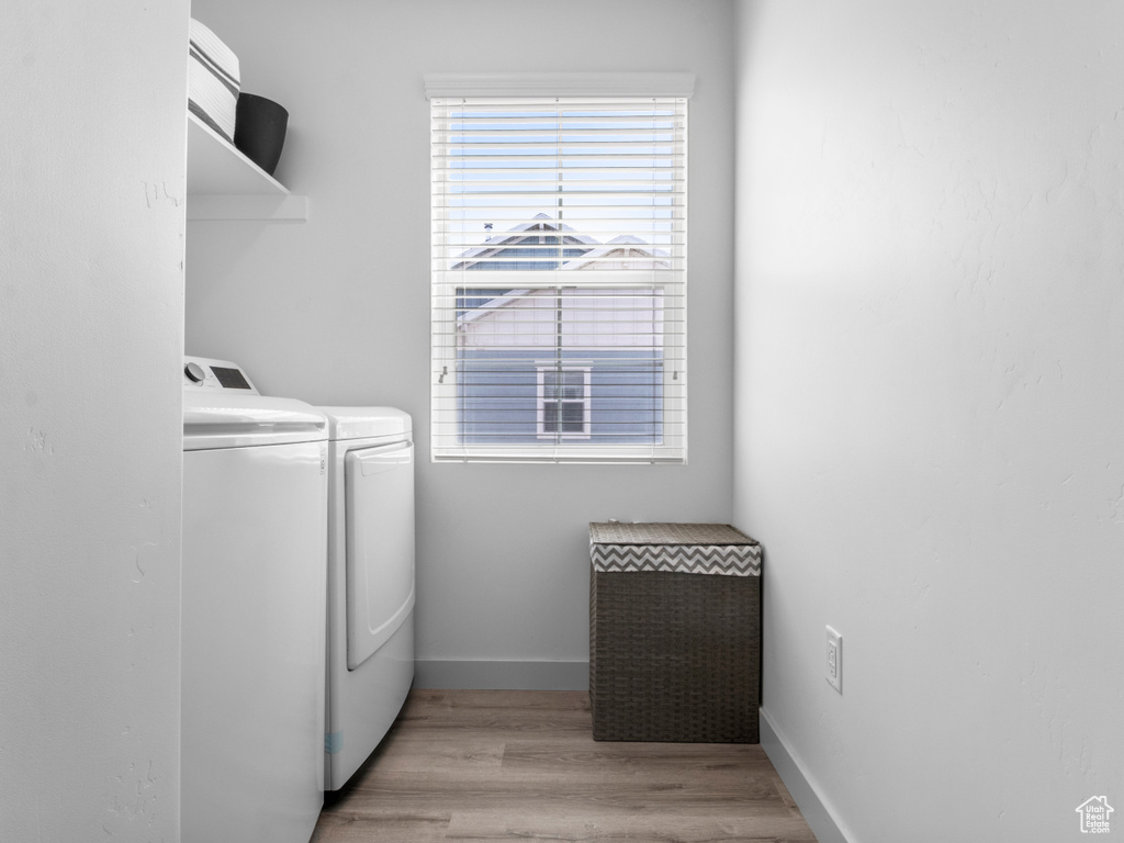 Clothes washing area featuring laundry area, baseboards, washer and dryer, and light wood-type flooring