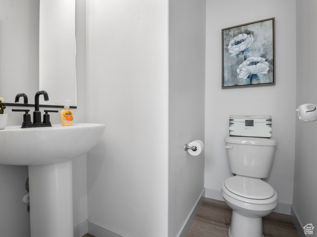 Bathroom with a sink, baseboards, toilet, and wood finished floors