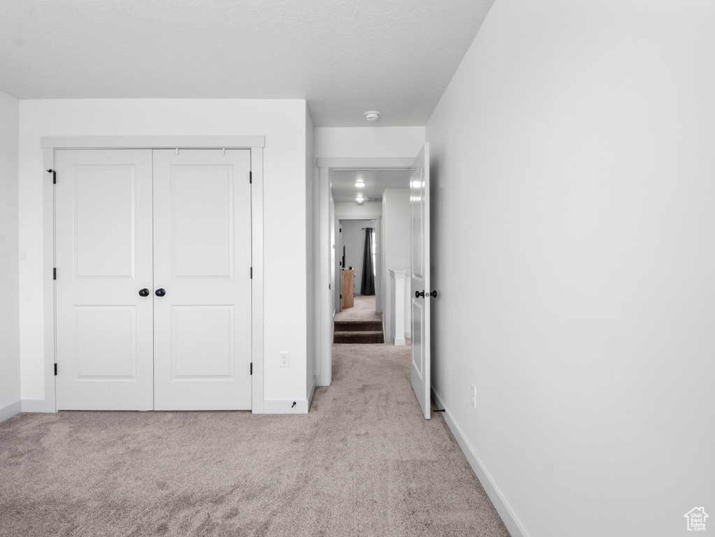 Unfurnished bedroom with baseboards, carpet, and a closet