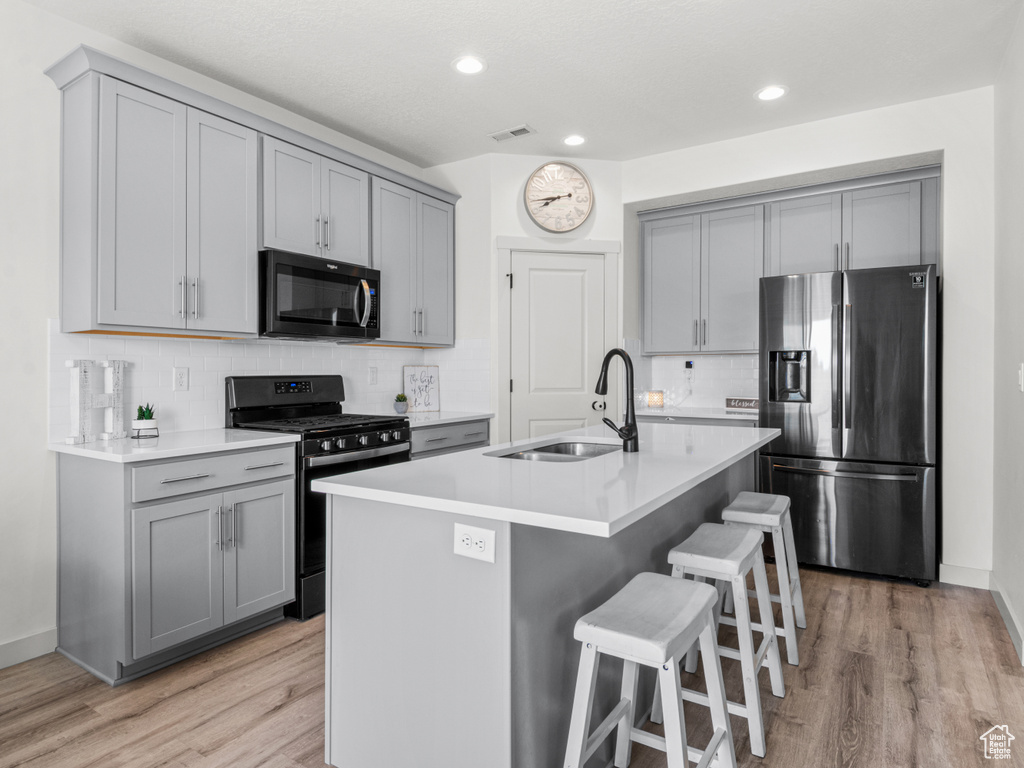 Kitchen featuring a sink, appliances with stainless steel finishes, gray cabinets, and light wood finished floors