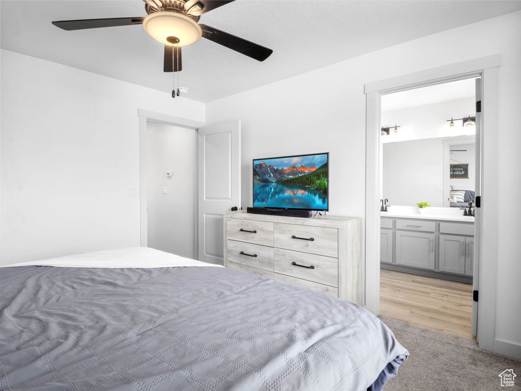 Bedroom with light carpet, a ceiling fan, and ensuite bath