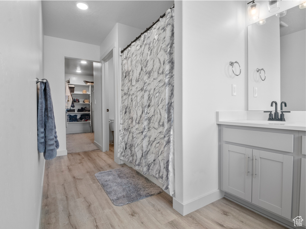 Bathroom with wood finished floors, vanity, baseboards, toilet, and recessed lighting