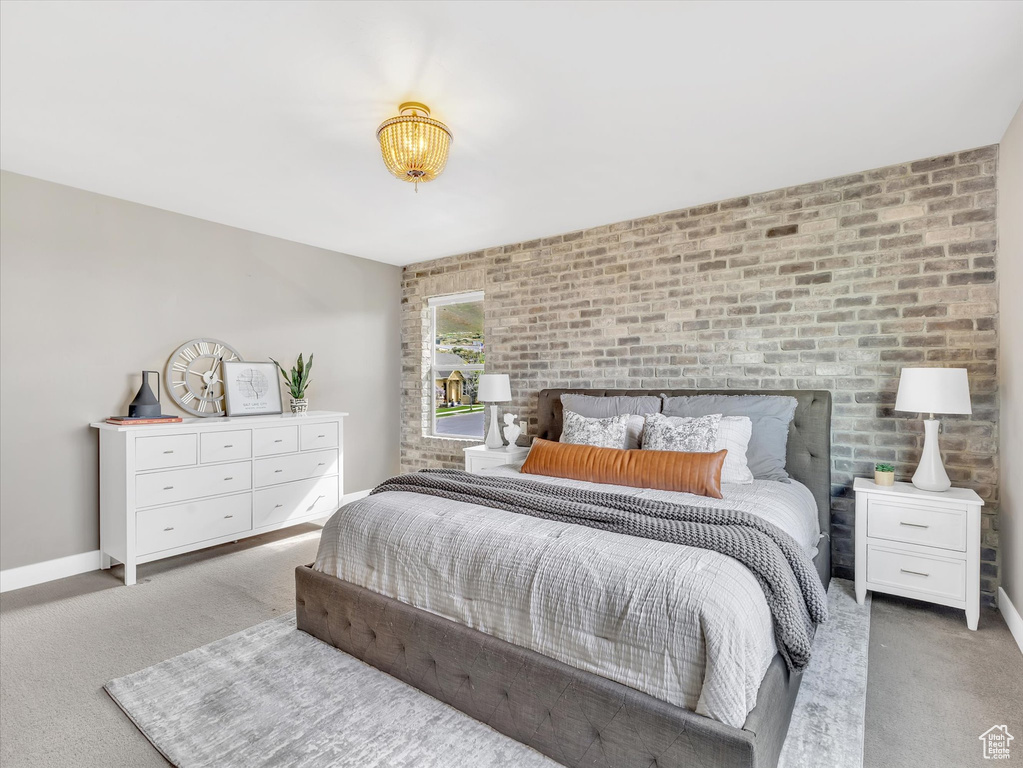 Bedroom with carpet floors, brick wall, and baseboards