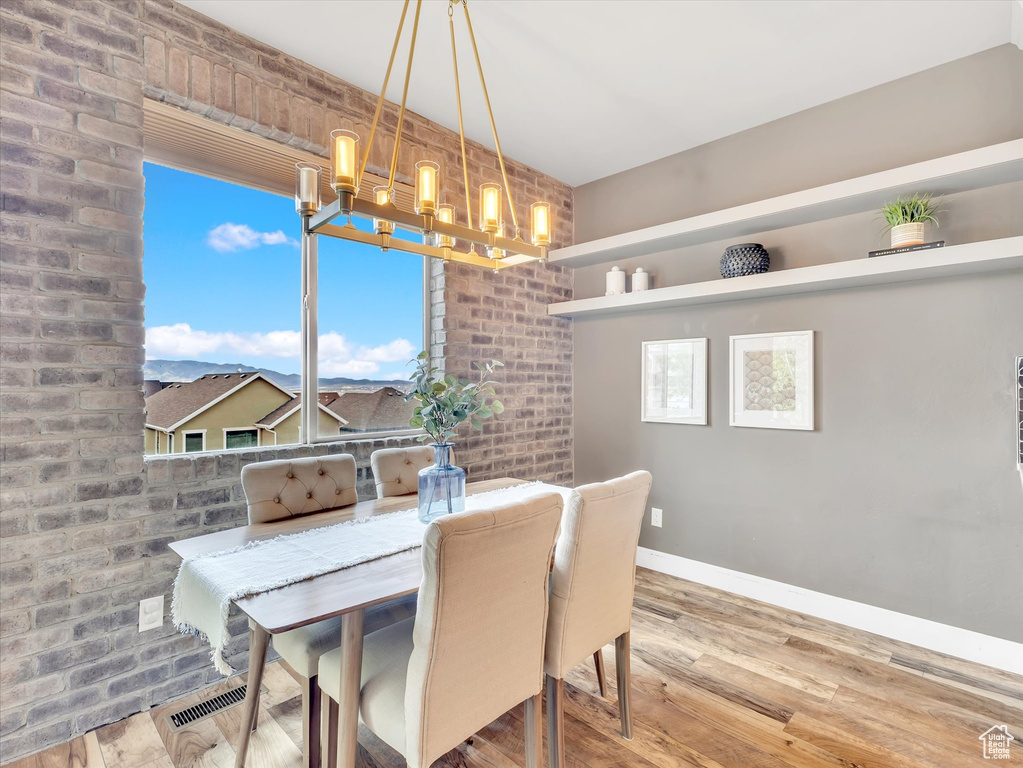 Dining space with baseboards, an inviting chandelier, wood finished floors, and visible vents