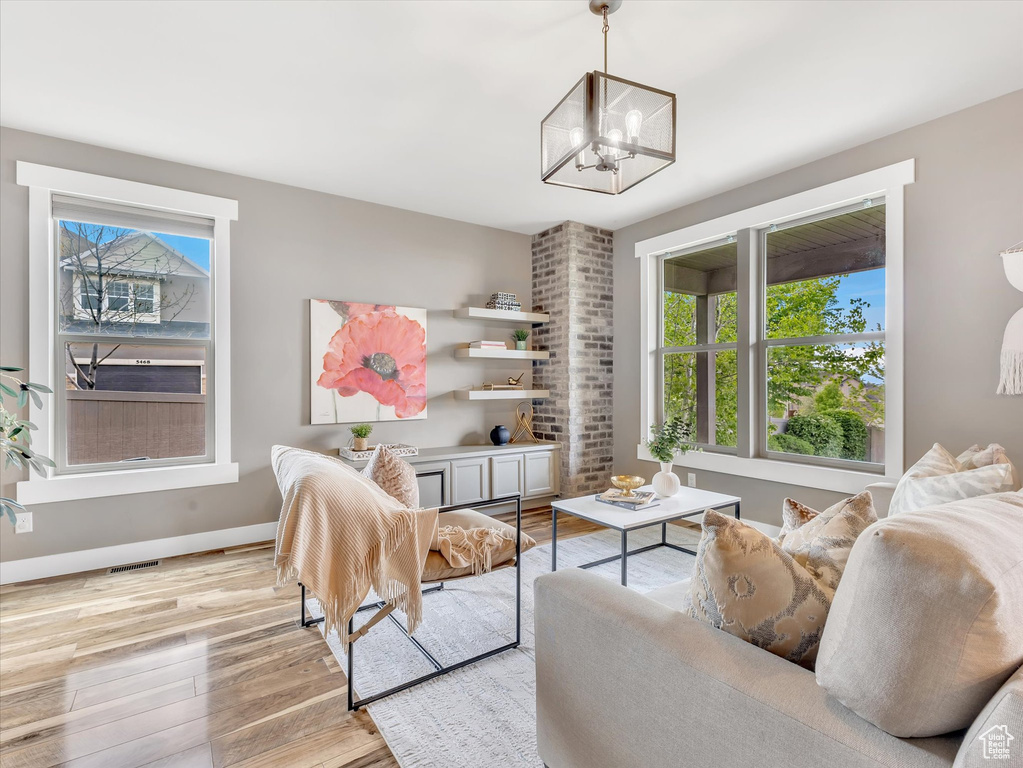 Living room with light wood-style floors, baseboards, a notable chandelier, and a wealth of natural light