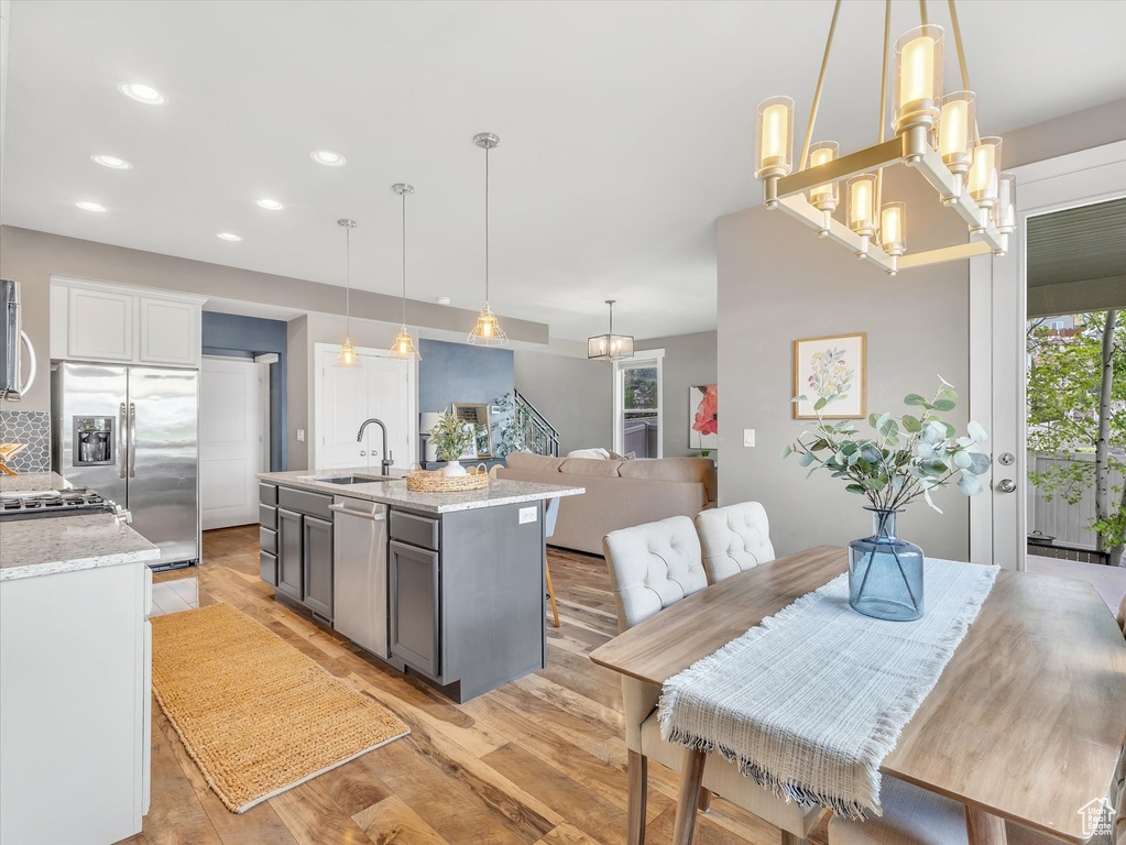 Kitchen featuring light stone countertops, light wood-style floors, recessed lighting, a sink, and stainless steel appliances
