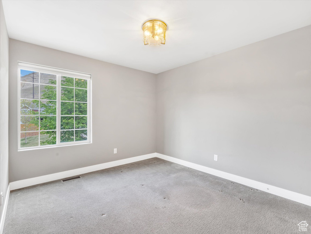 Carpeted spare room featuring baseboards and visible vents