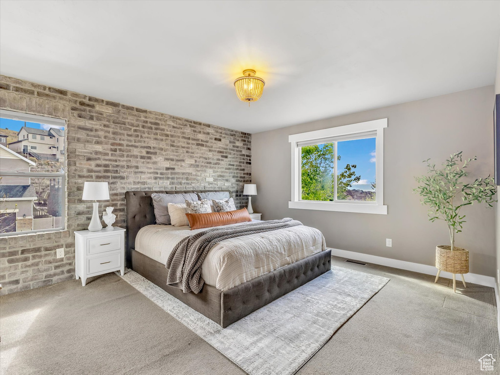 Bedroom with carpet floors, baseboards, brick wall, and visible vents