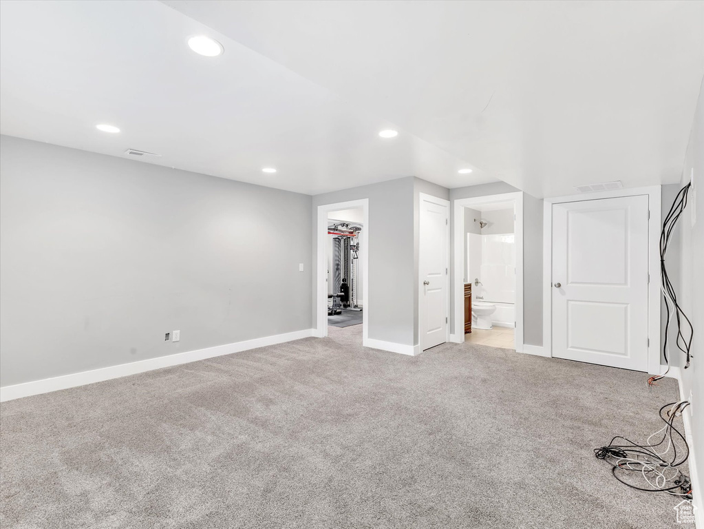 Unfurnished bedroom featuring light colored carpet, baseboards, connected bathroom, a spacious closet, and recessed lighting