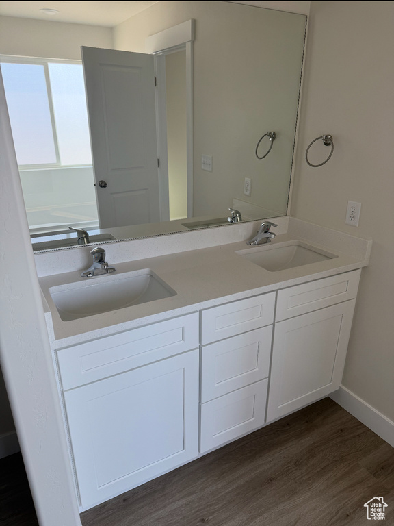Full bathroom featuring double vanity, a sink, and wood finished floors