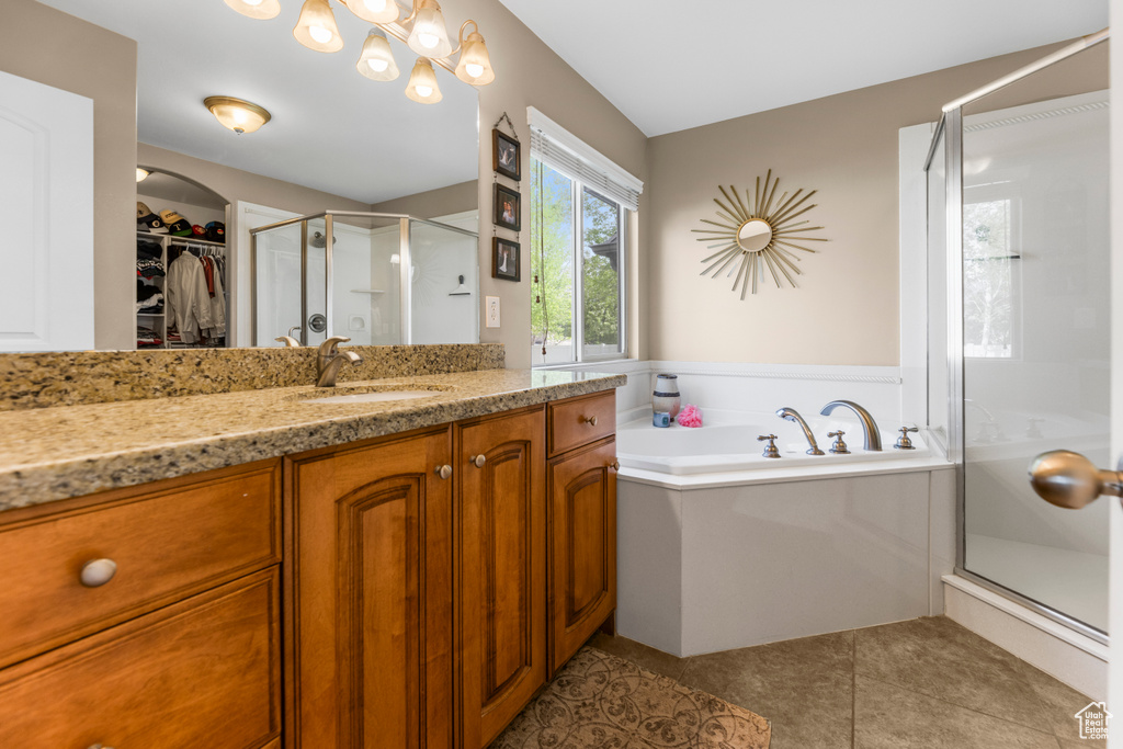 Full bathroom featuring a walk in closet, a garden tub, tile patterned flooring, a shower stall, and vanity