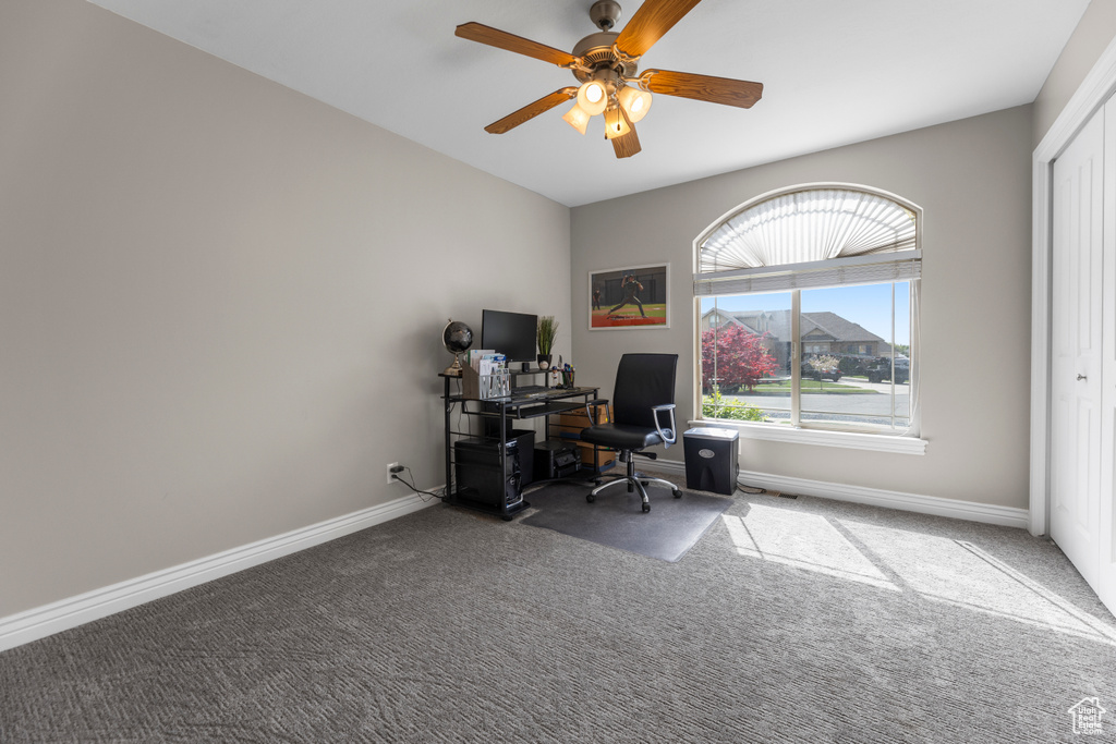 Carpeted office space featuring baseboards and ceiling fan