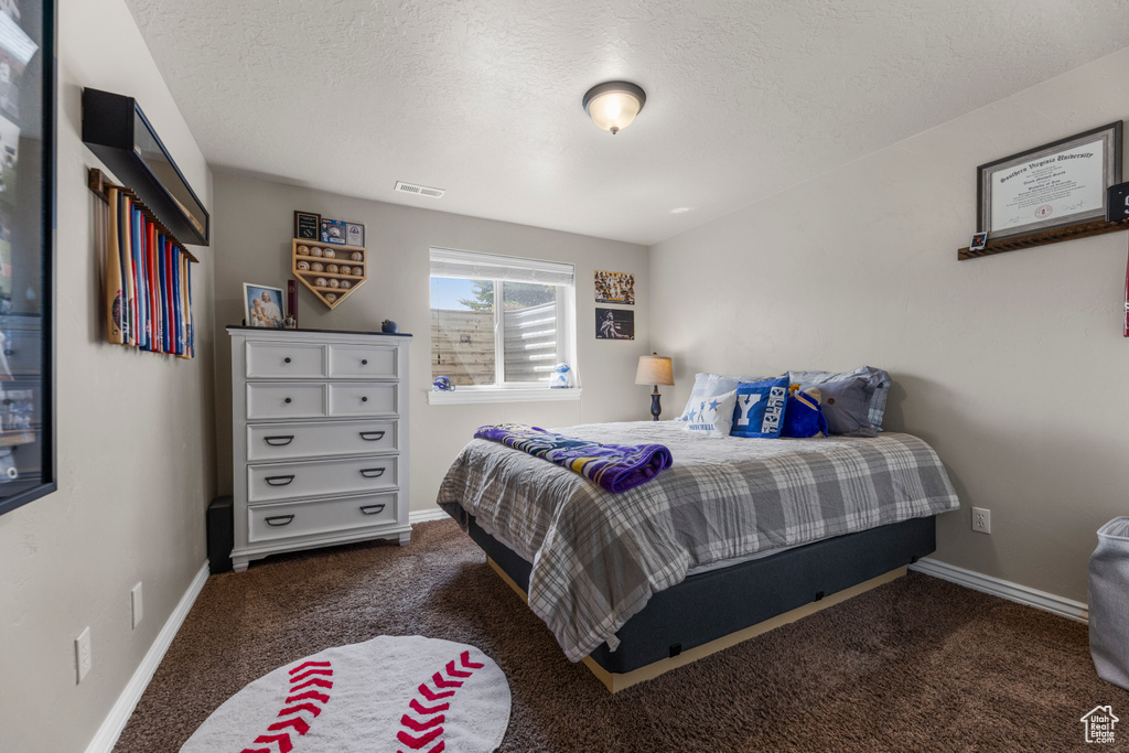 Carpeted bedroom with a textured ceiling, visible vents, and baseboards