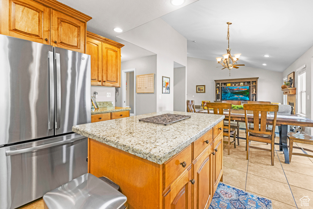 Kitchen with an inviting chandelier, light stone counters, freestanding refrigerator, recessed lighting, and a kitchen island