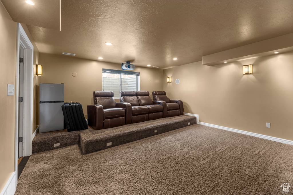 Carpeted home theater featuring baseboards, recessed lighting, a textured ceiling, and visible vents