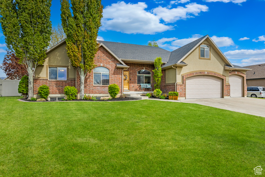 View of front of home with driveway, a front yard, fence, an attached garage, and a shingled roof