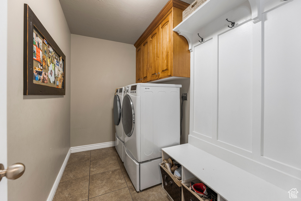 Laundry room with baseboards, washer and clothes dryer, cabinet space, and tile patterned flooring