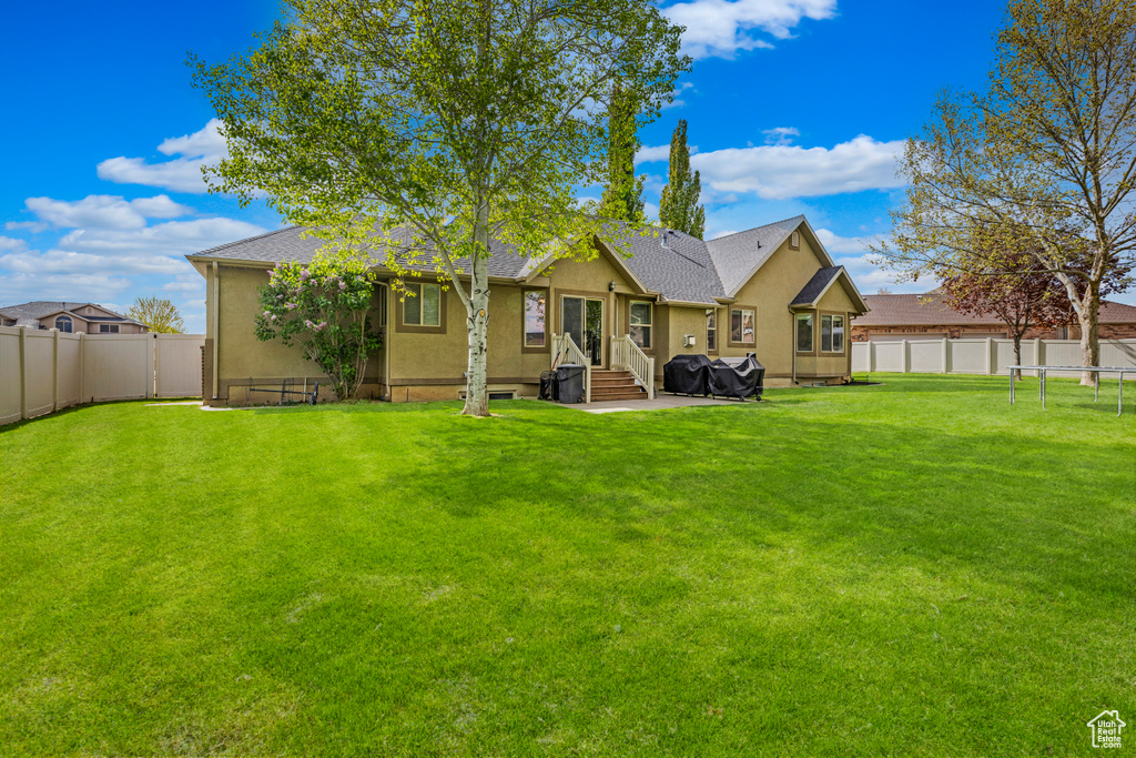 Rear view of house with a lawn, a fenced backyard, and stucco siding