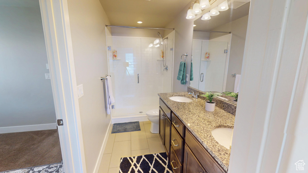 Bathroom with a sink, tile patterned flooring, double vanity, toilet, and a shower stall