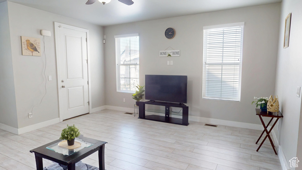 Living room featuring light wood-type flooring, a ceiling fan, and a wealth of natural light