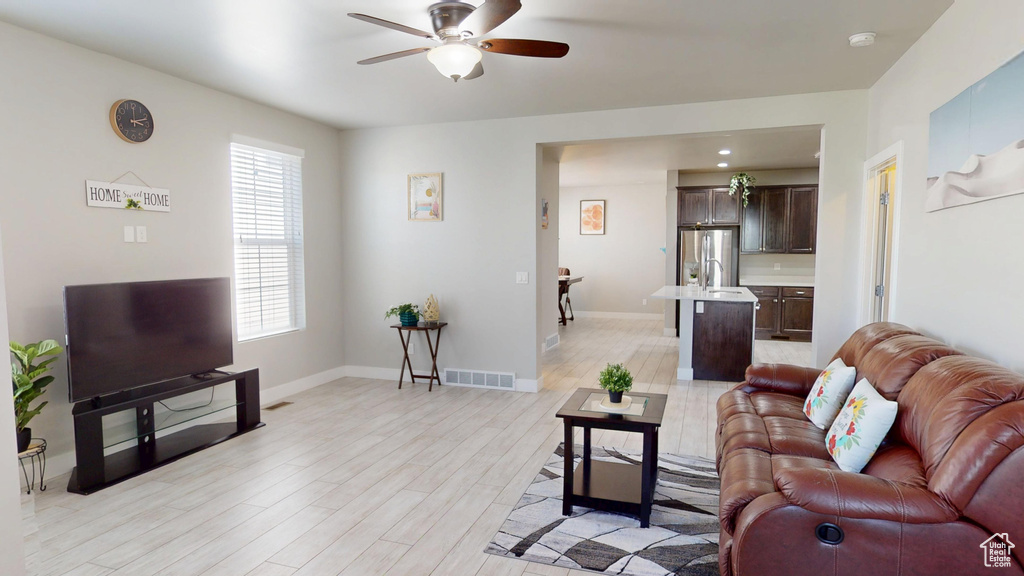 Living room with light wood-style floors, a ceiling fan, baseboards, and visible vents