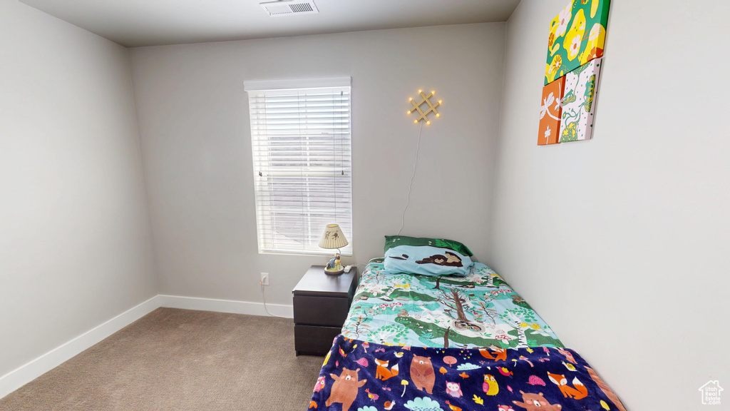 Carpeted bedroom featuring baseboards, visible vents, and multiple windows