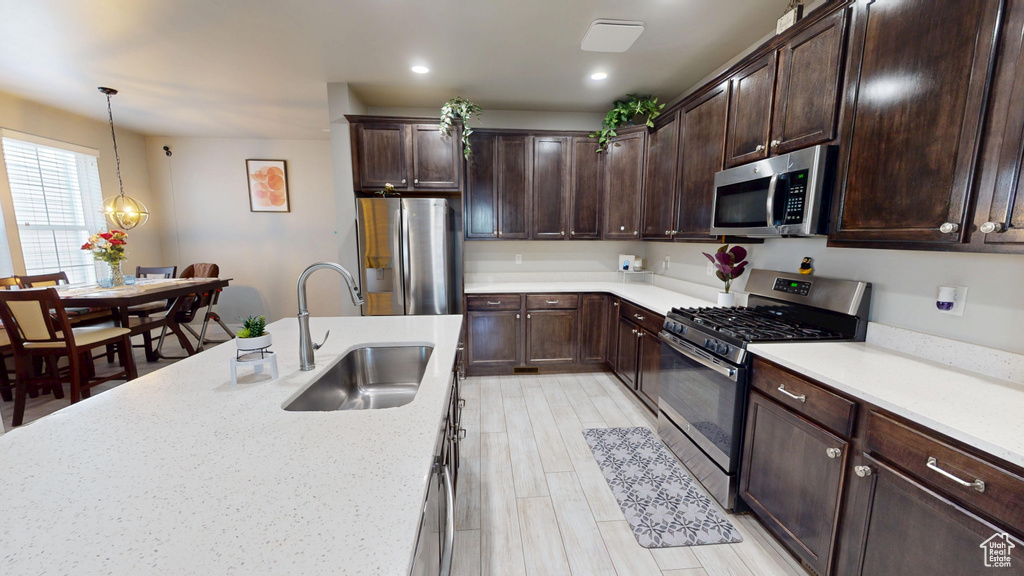 Kitchen featuring a sink, hanging light fixtures, dark brown cabinets, and stainless steel appliances