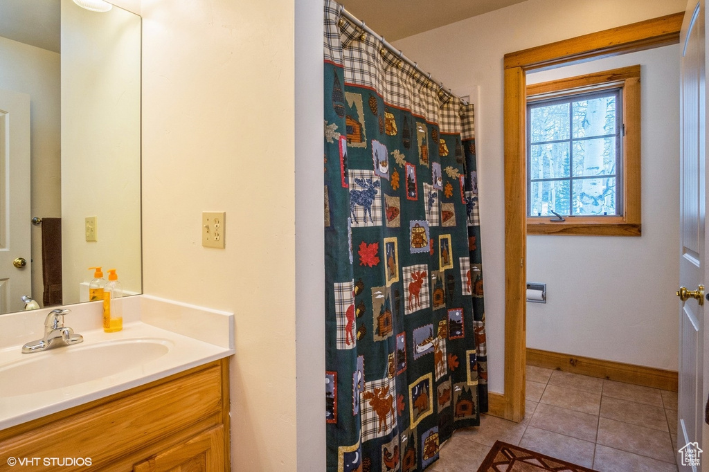 Full bathroom featuring vanity, tile patterned flooring, baseboards, and a shower with shower curtain
