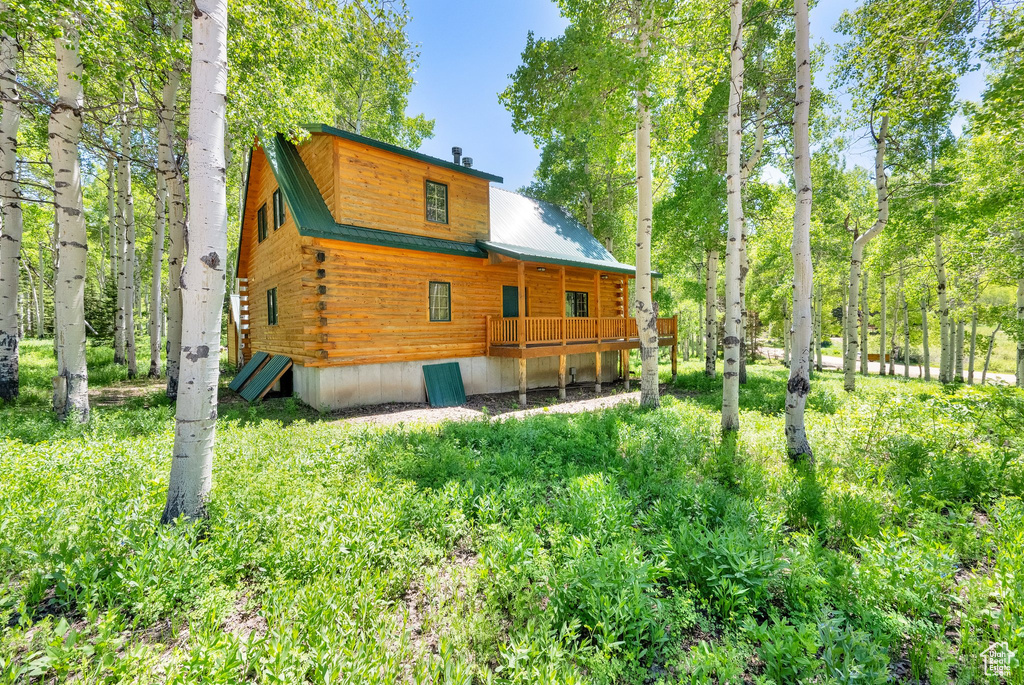 Back of house with metal roof and log siding