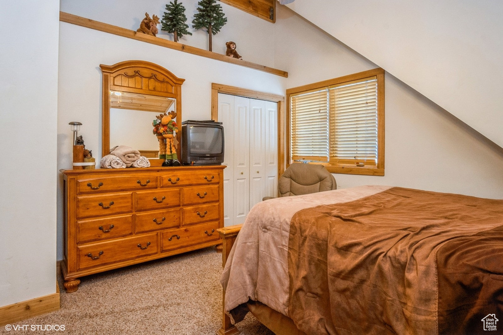 Bedroom featuring light colored carpet, lofted ceiling, and a closet