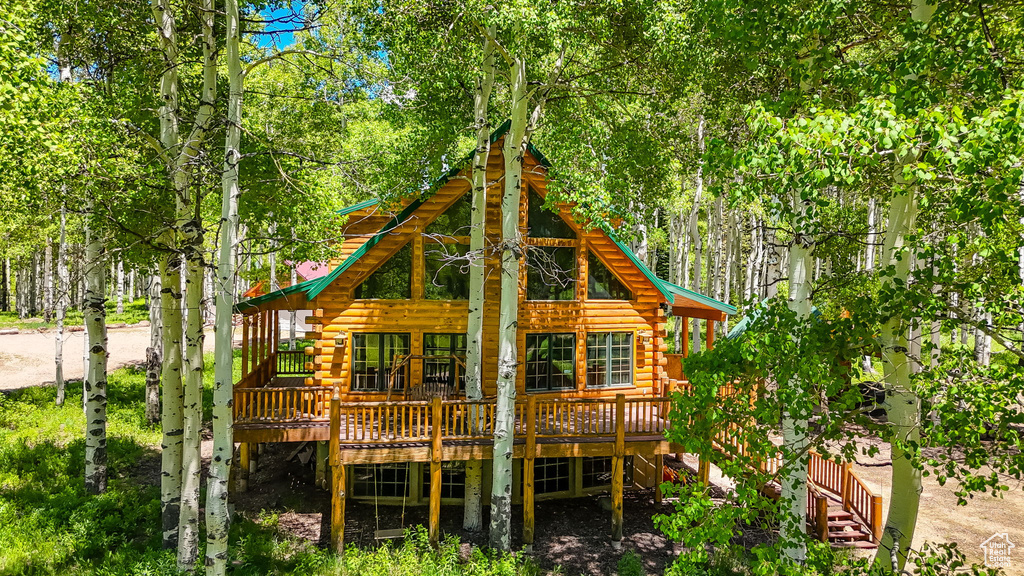 Back of house with log exterior and a deck