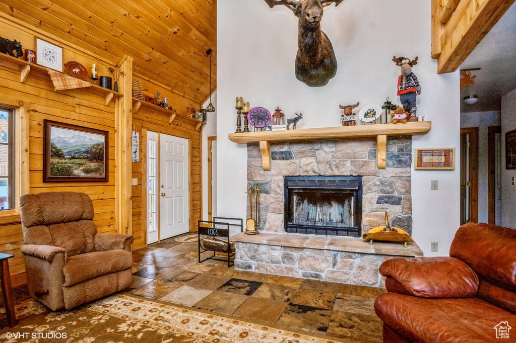 Living area with wood ceiling, a fireplace, wood walls, high vaulted ceiling, and stone tile flooring