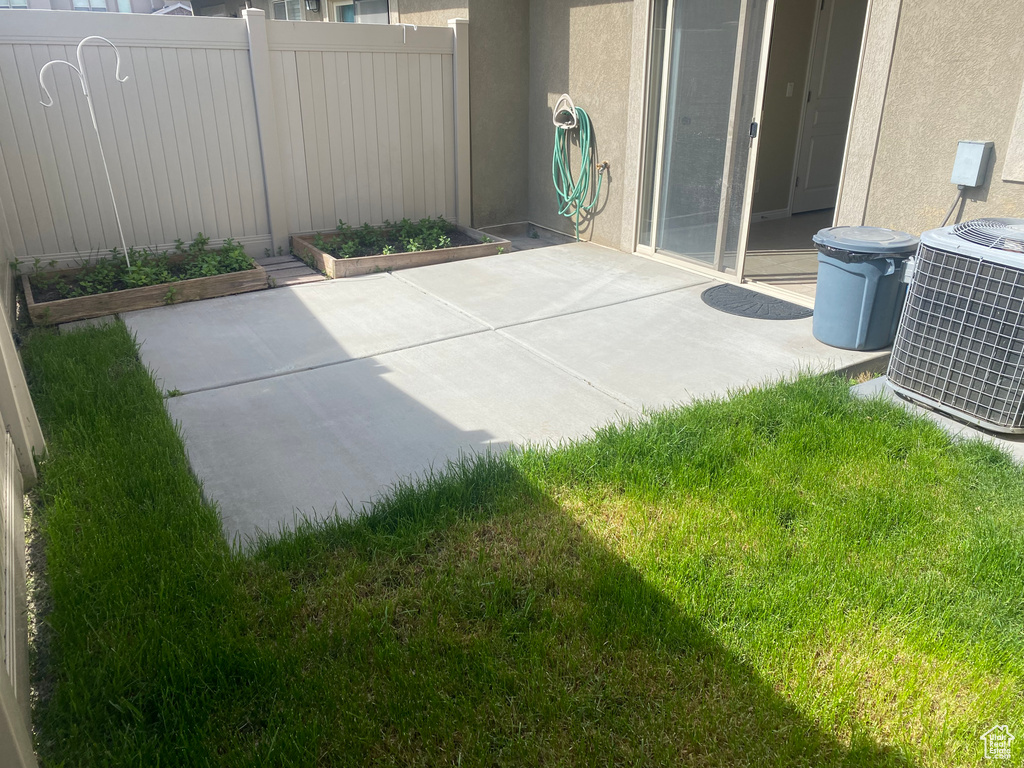 View of patio / terrace featuring a garden, central air condition unit, and fence