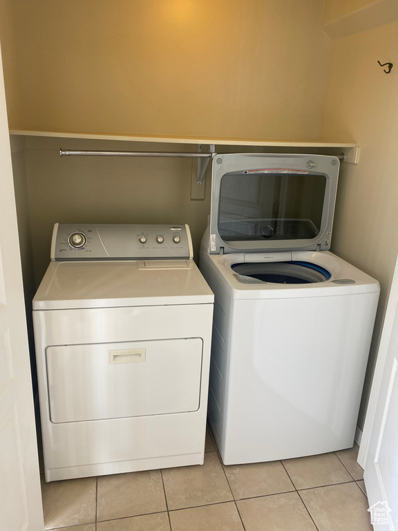 Laundry room with independent washer and dryer, light tile patterned flooring, and laundry area