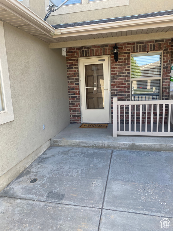 Doorway to property featuring a porch, brick siding, and stucco siding