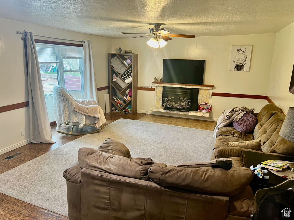 Living area featuring visible vents, wood finished floors, baseboards, ceiling fan, and a textured ceiling