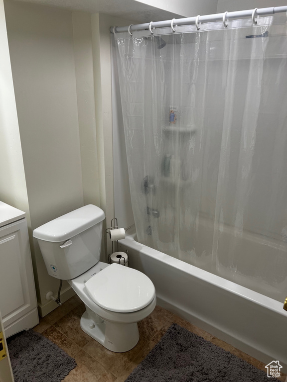 Bathroom featuring tile patterned flooring, toilet, and shower / bathtub combination with curtain