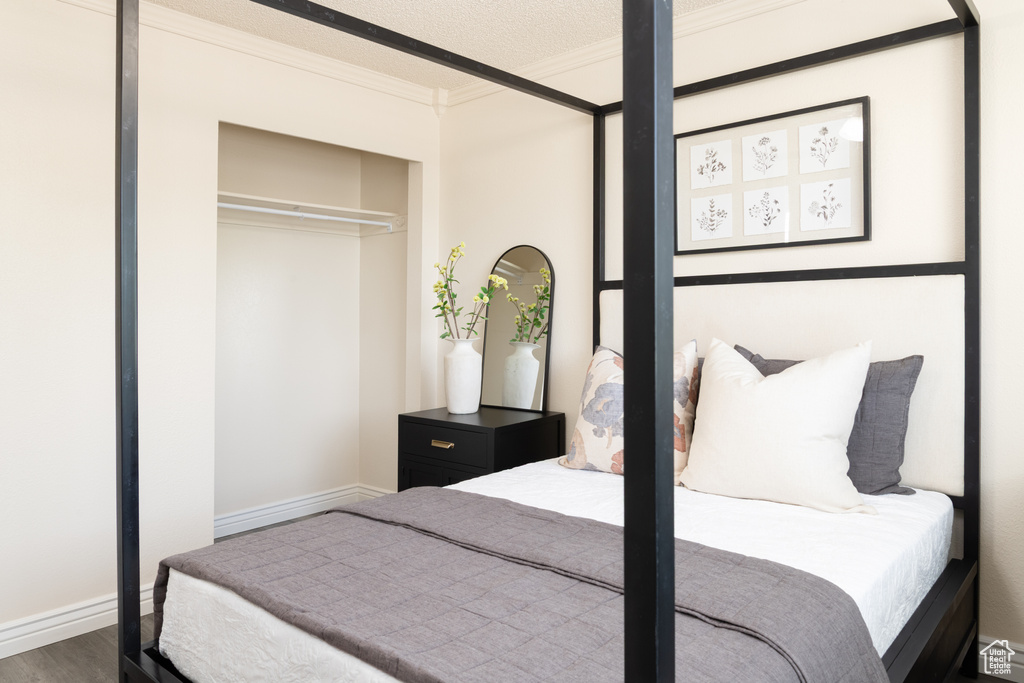 Bedroom with crown molding, baseboards, and wood finished floors