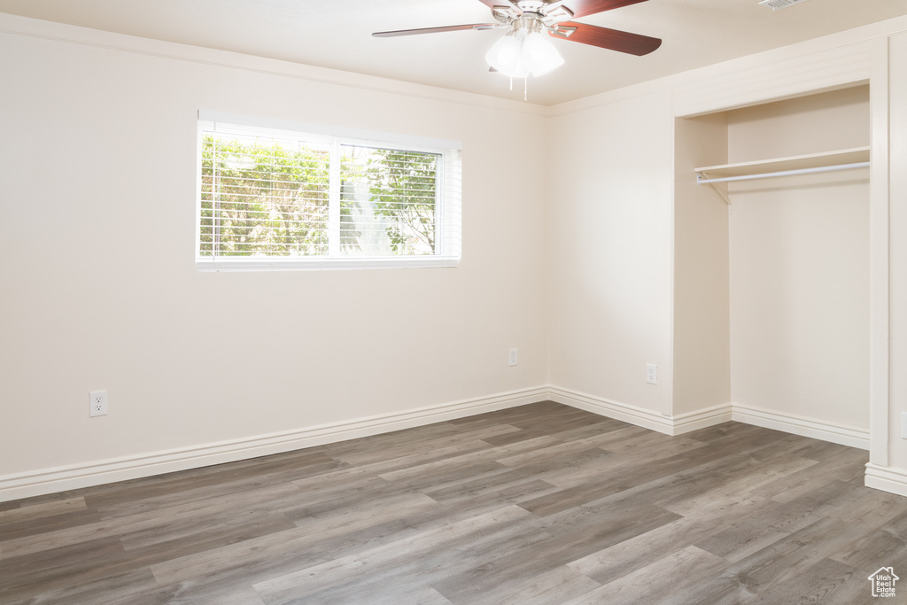 Unfurnished bedroom featuring baseboards, ceiling fan, a closet, and wood finished floors