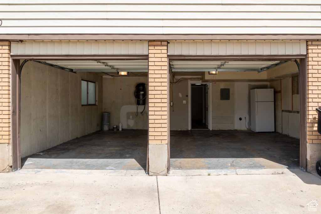 Garage featuring freestanding refrigerator, driveway, and a garage door opener